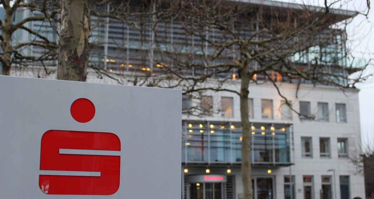 Zu sehen ist ein Sparkassen-Schild mit dem roten Logo vor der Wilhelmshavener Sparkassen-Filiale am Theaterplatz.