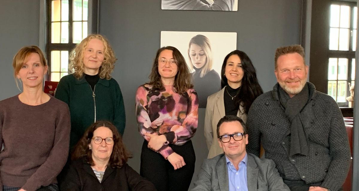 Auf dem Foto sind die Organisator*innen des Kulturkarussells 2025 zu sehen. Von links: Diana Bogdanski (VHS Wilhelmshaven), Petra Stegmann (Kunsthalle Wilhelmshaven), Ines Mierau (sitzend, VHS Wilhelmshaven), Stela Dujakovic (Kulturbüroleiterin), Sarah Helmy (Pressesprecherin der Landebühne Niedersachsen-Nord), Armin Schönfelder (sitzend, Erster Stadtrat) und Olaf Strieb (Intendant Landesbühne Niedersachsen-Nord). Es fehlt Jan-Helge Ralle von der Stadtbibliothek.