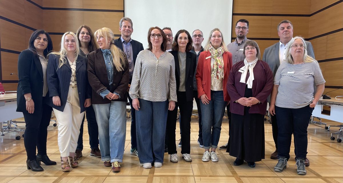 Zu sehen sind Verter*inen der Institutionen des Netzwerkes Migrationsberatung, die sich im Wilhelmshavener Ratsaal für ein Foto versammelt haben.