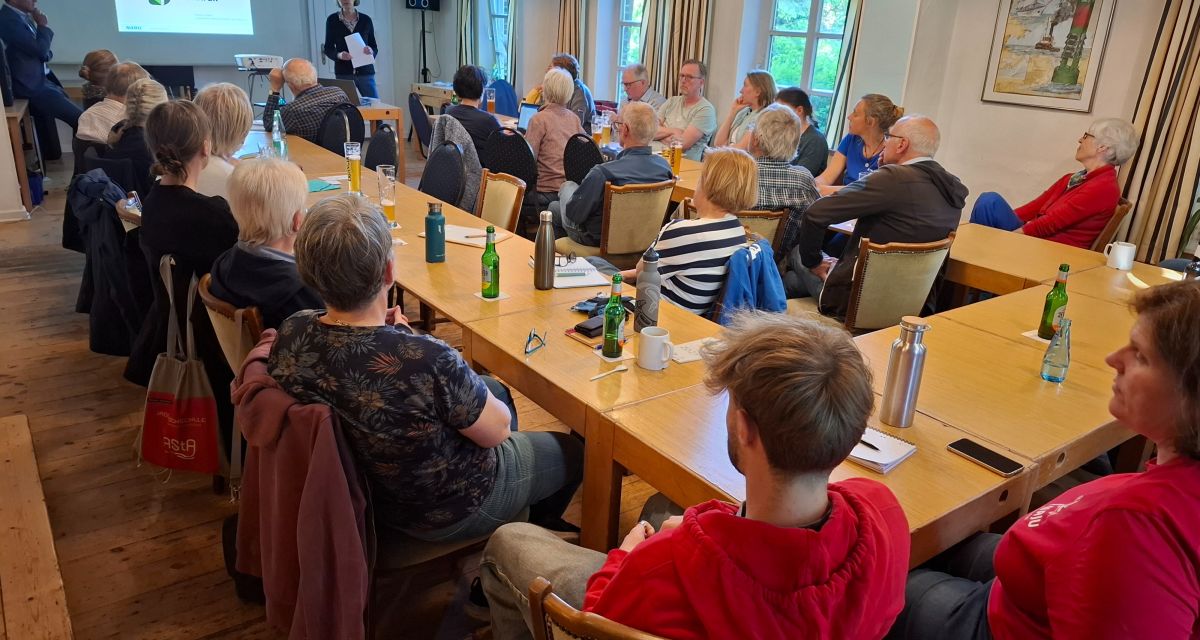 Eine Menschengruppe betrachtet eine Präsentation auf einer Leinwand mit dem Titel