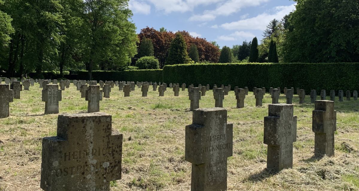 Auf dem Foto sind Grabsteine auf dem Ehrenfriedhof in Wilhelmshaven zu sehen. Sie stehen in geraden Reihen und haben die Form von schlichten Steinkreuzen. Die fotografierten Grabmäler stehen auf dem Gräberfeld für Gefallene des Ersten Weltkriegs. 