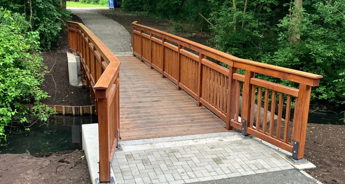 Zu sehen ist die im Mai 2025 fertiggestellte Fußgängerbrücke im Wilhelmshavener Stadtteil Altengroden. Die Holzbrücke führt über ein kleineres Gewässer und verbindet die Straße