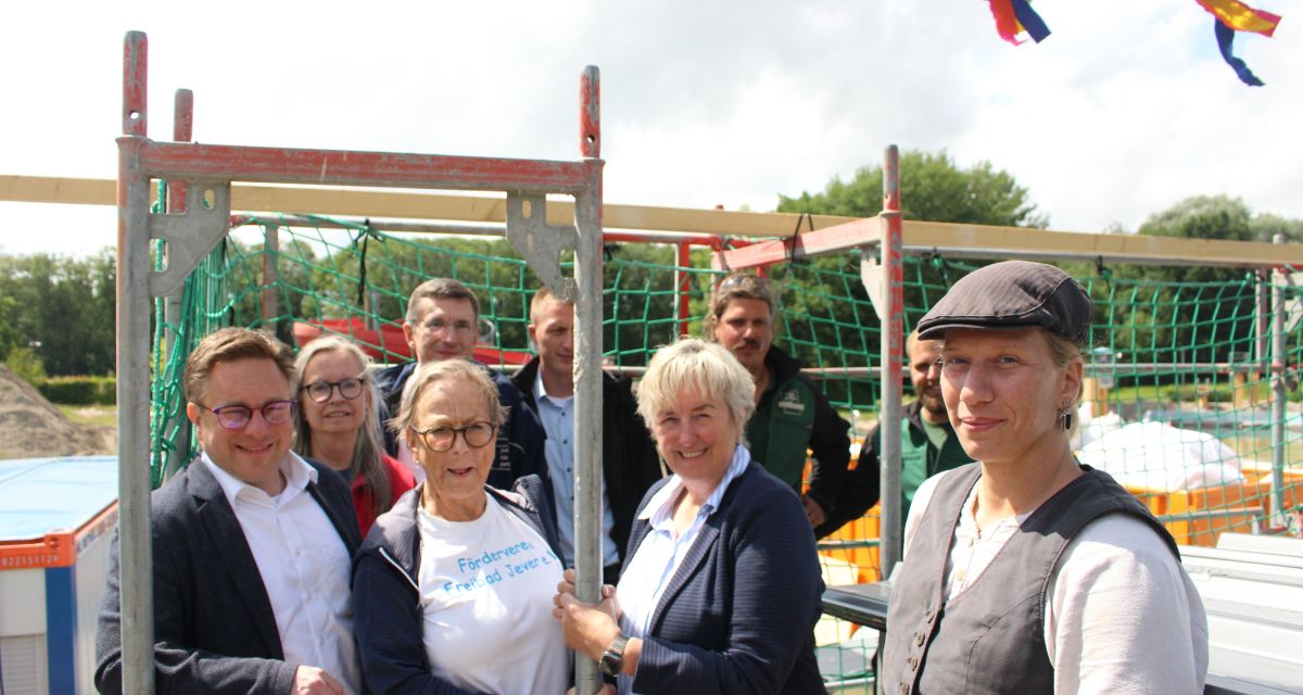 Vertreter*innen von Jeverscher Politik, Handwerk, Planung und Förderern stehen auf dem Dach des Gebäudes des Johann-Rasenack-Freibades in Jever anlässlich des Richtfestes, unter anderem Jevers Bürgermeister Jan Edo Albers.