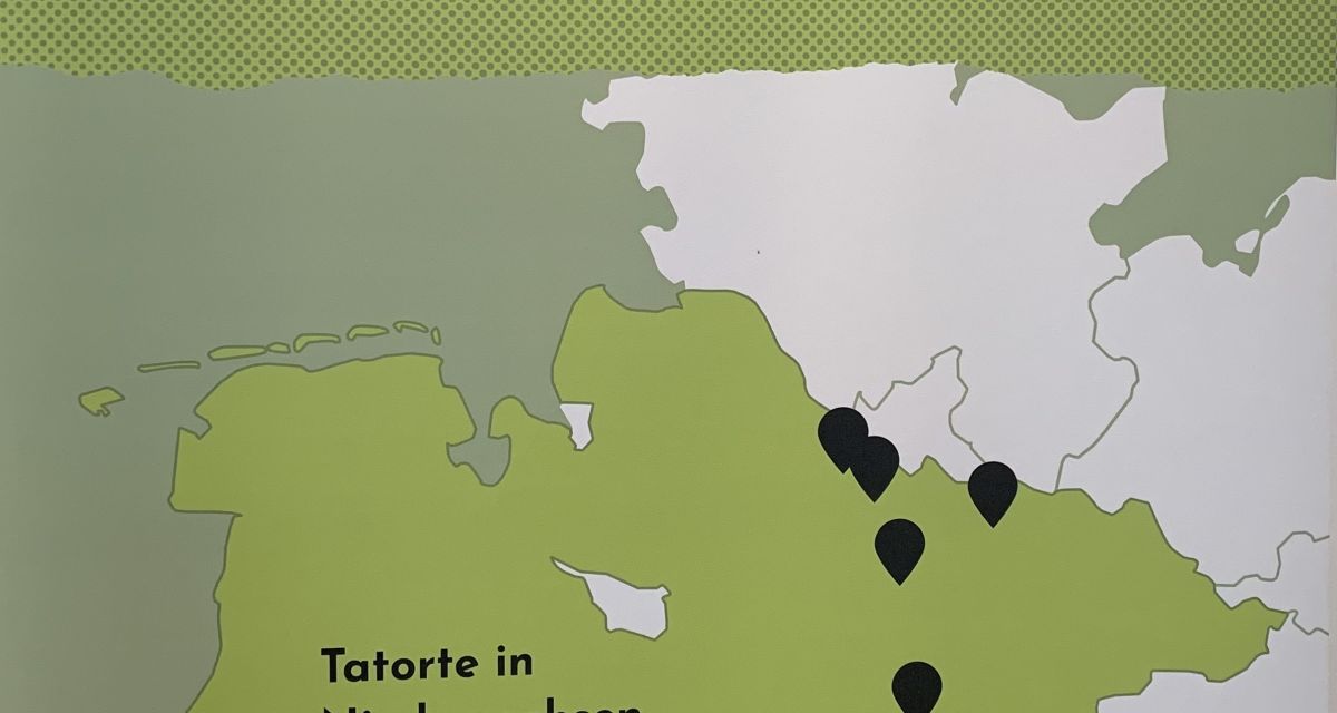 Auf dem Foto ist eine Roll-Up-Tafel zu sehen. Auf ihr steht der vollständige Titel der Ausstellung