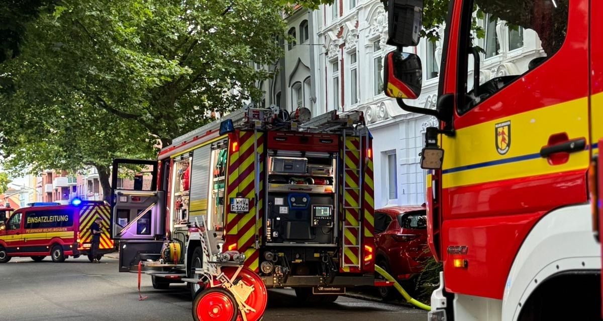 Zu sehen sind Einsatzfahrzeuge der Feuerwehr Wilhelmshaven in der Rheinstraße in der Südstraße. In der Bildmitte steht ein Löschfahrzeug mit ausgerollten Löschschläuchen.