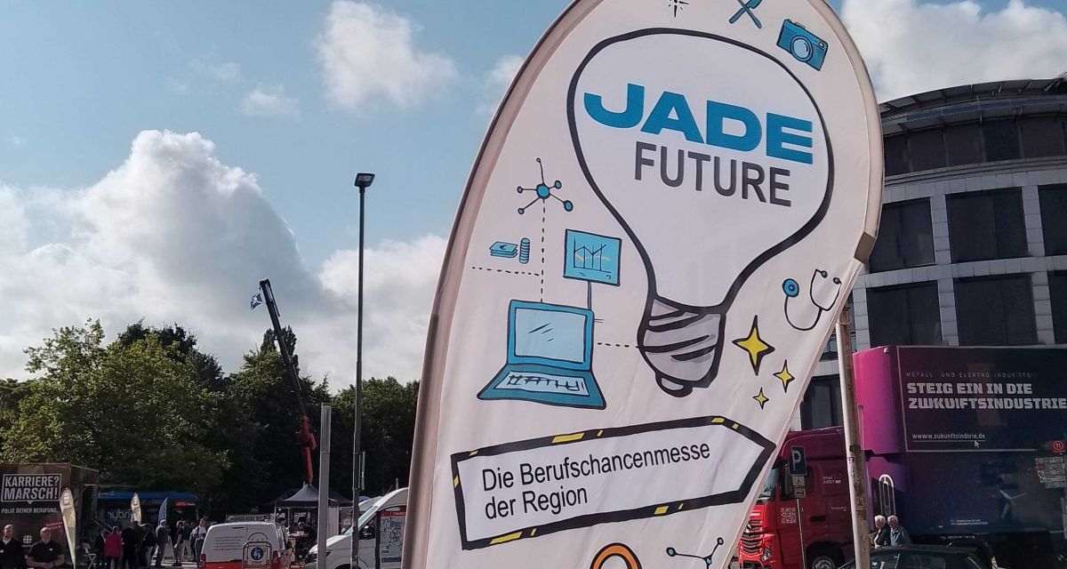 Zu sehen ist eine Beachflag vor der Nordseepassage in Wilhelmshaven. Darauf geschrieben steht