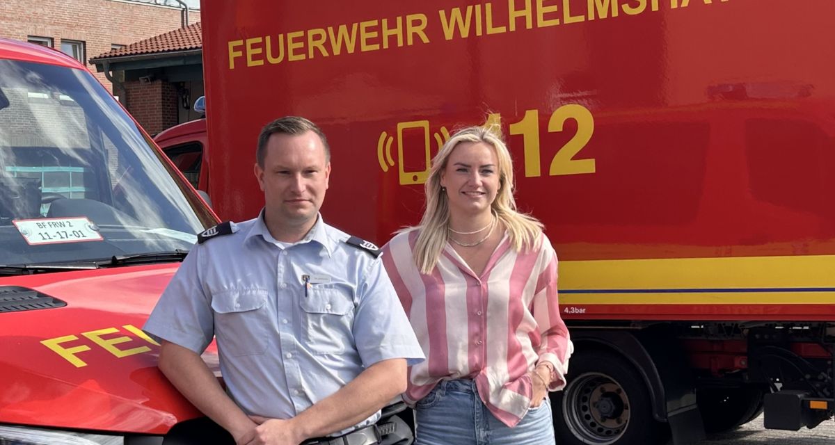 Tim Schriemer (Bevölkerungsschutz bei der Feuerwehr WHV) und Marinie Menkens (GF VKP) vor Feuerwehrfahrzeugen