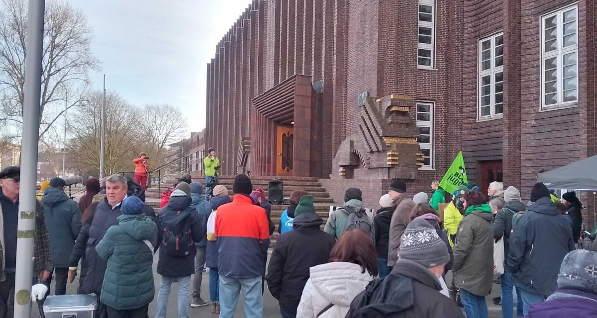 Zu sehen ist eine Protestkundgebung vor dem Wilhelmshavener Rathaus, zu der ein Bündnis aus Umwelt- und Naturschutzverbänden, Wissenschaft und Zivilgesellschaft aufgerufen hat. Anlass ist eine Ratabstimmung über die Zukunft des Natur- und Vogelschutzgebietes auf dem Voslapper Groden-Nord.