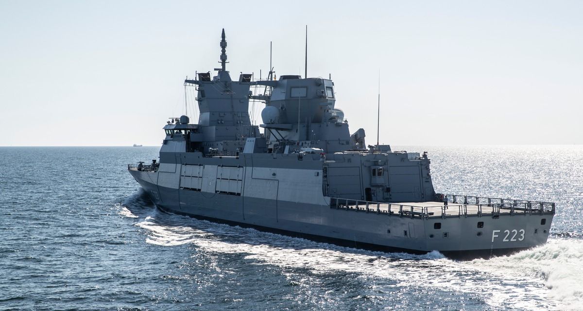 Die Fregatte F 223 der Deutschen Marine. Das Schiff fährt vom Betrachter weg auf das offene Meer, gut zu erkennen sind das Heck und das Achterdeck.