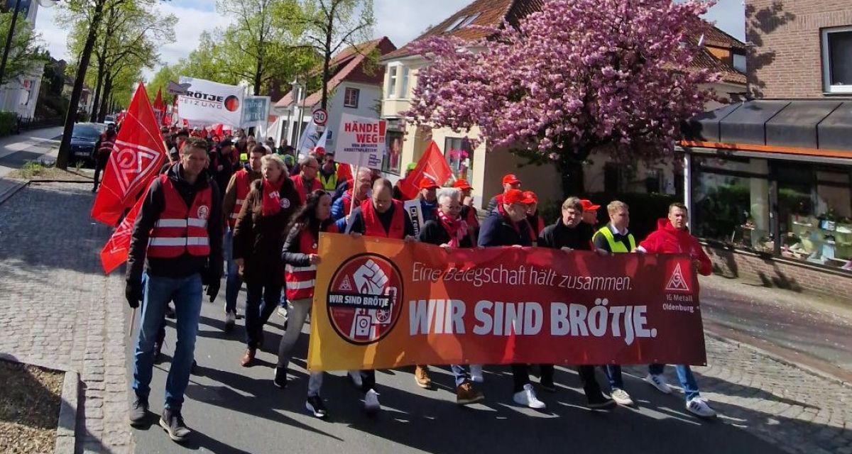 Menschen laufen mit Bannern und Schildern durch Rastede. 