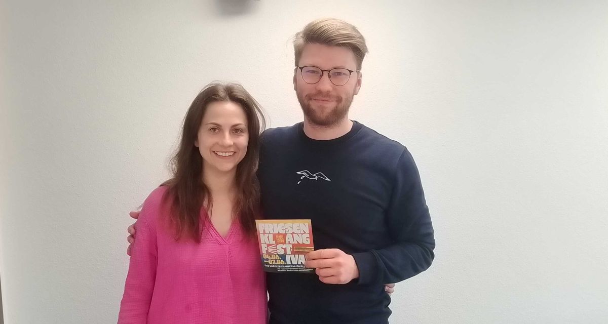 Die Organisator*innen des Friesenklang Festivals für Kammermusik in Varel stehen im Studio von Radio Jade, von links nach rechts Victoria Poli und Alexander Vorontsov, in Hände hält Vorontsov den Flyer des Festivals.