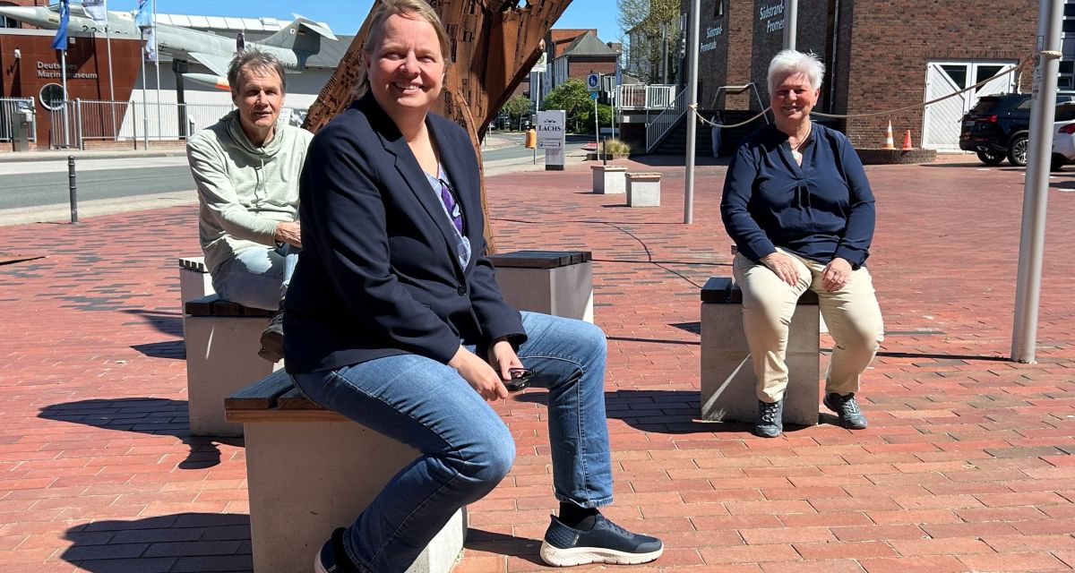 Zu sehen sind drei Menschen, sitzend vor  der metallenen Walskulpptur am Wattenmeer-besucherzentrum in Wilhelmshaven an einem sonnigen Tag: Von links: Wolf-Dietrich Hufenbach (Zukunftswerkstatt Wilhelmshaven), Stefanie Eilers (NABU) und Karin Boldt (Wattenmeerhaus)