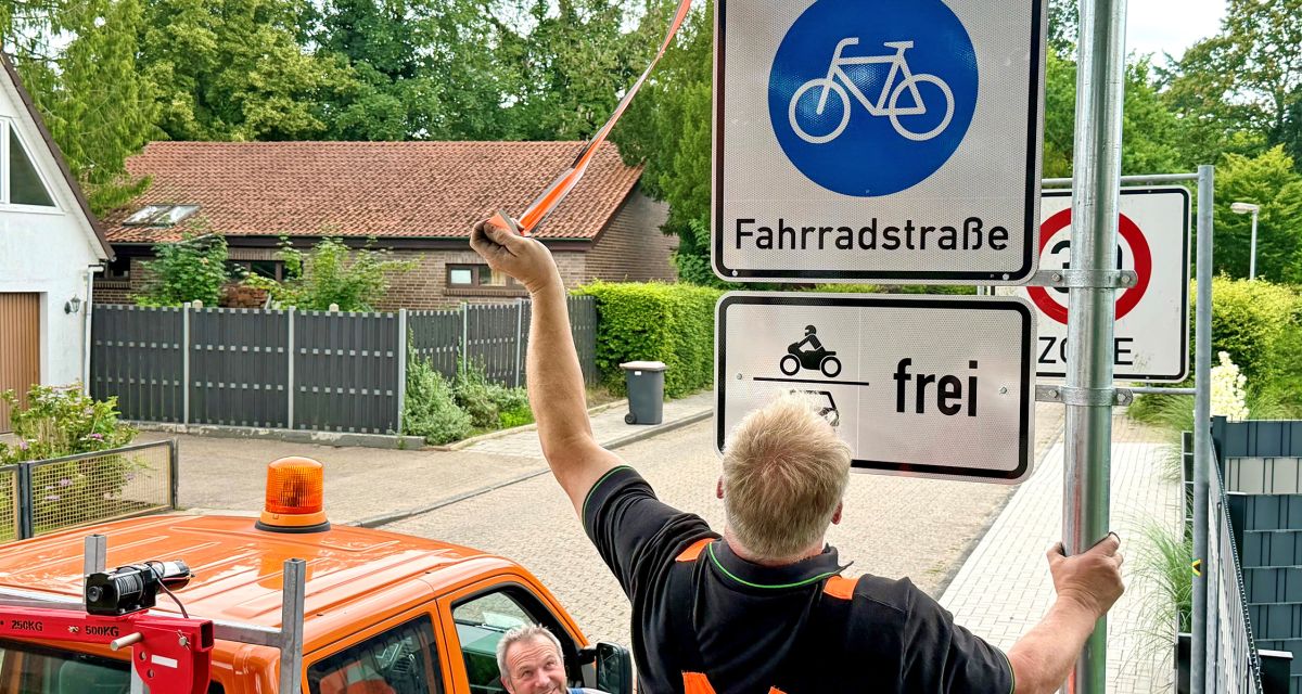 Mitarbeiter der Stadt Varel installieren ein Hinweisschild an der neuen Fahrradstraße auf der Osterstraße.