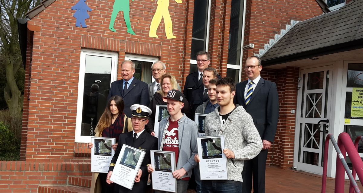 Mehrere Menschen stehen auf einer Treppe, einige von ihnen halten Urkunden.