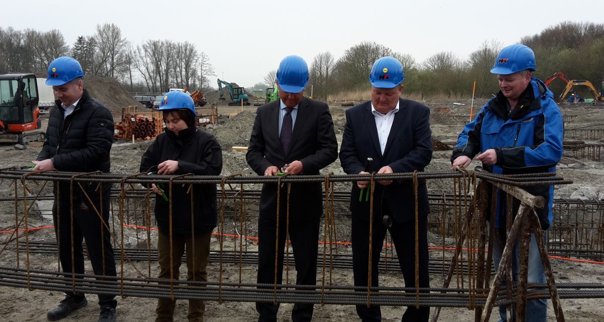 Mehrere Personen, darunter Wilhelmshavens Oberbürgermeister Andreas Wagner, befestigen Drähte auf dem Baugelände
