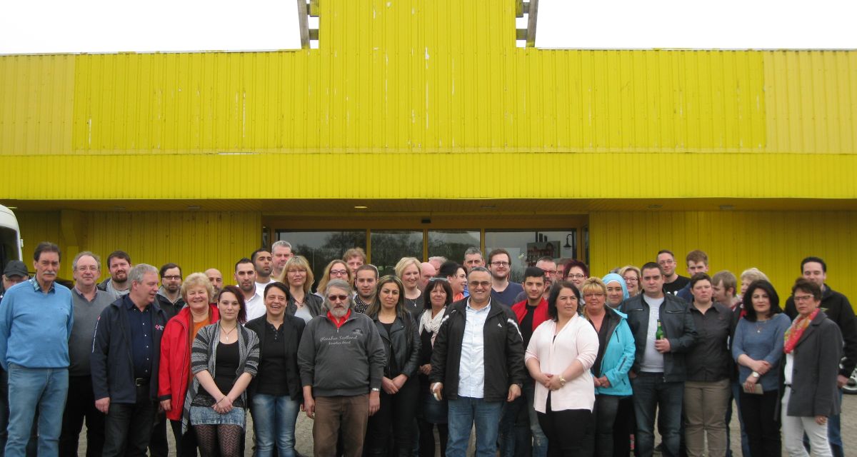 Viele Menschen, darunter Flüchtlinge, posieren für die Kamera.