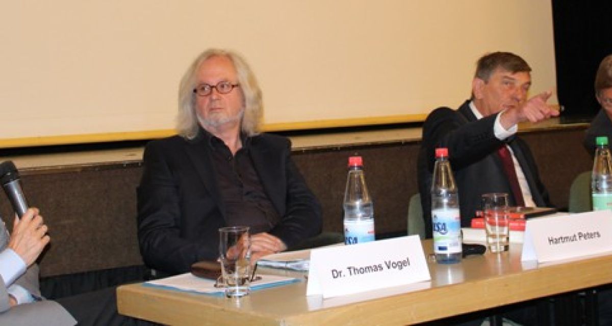 Vier Männer sitzen bei einer Podiumsdiskussion am Tisch.