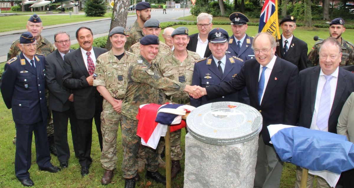 Männer in Bundeswehruniform und in Zivil schütteln sich die Hände, Gruppe steht dahinter