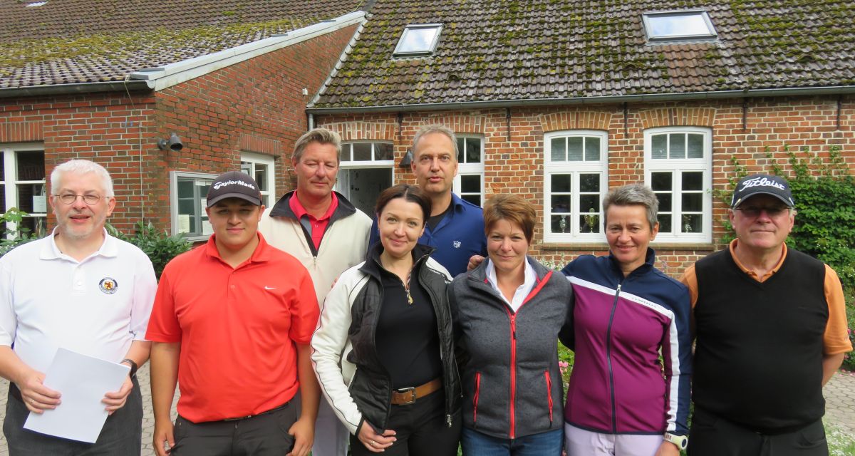 Zu sehen sind ein paar Mitglieder des Wilhelmshavener Golfclubs vor einem Backsteinhaus.