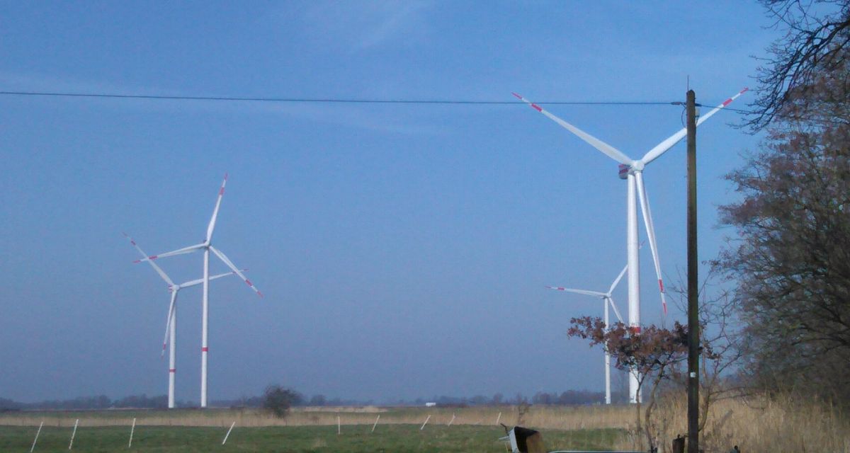 Zu sehen sind vier Windräder vor blauem Himmel.