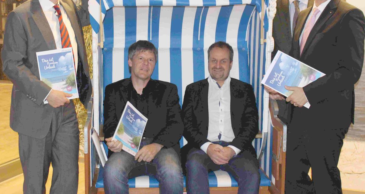 Fünf Männer, zwei in einem Strandkorb sitzend, posieren für die Kamera.