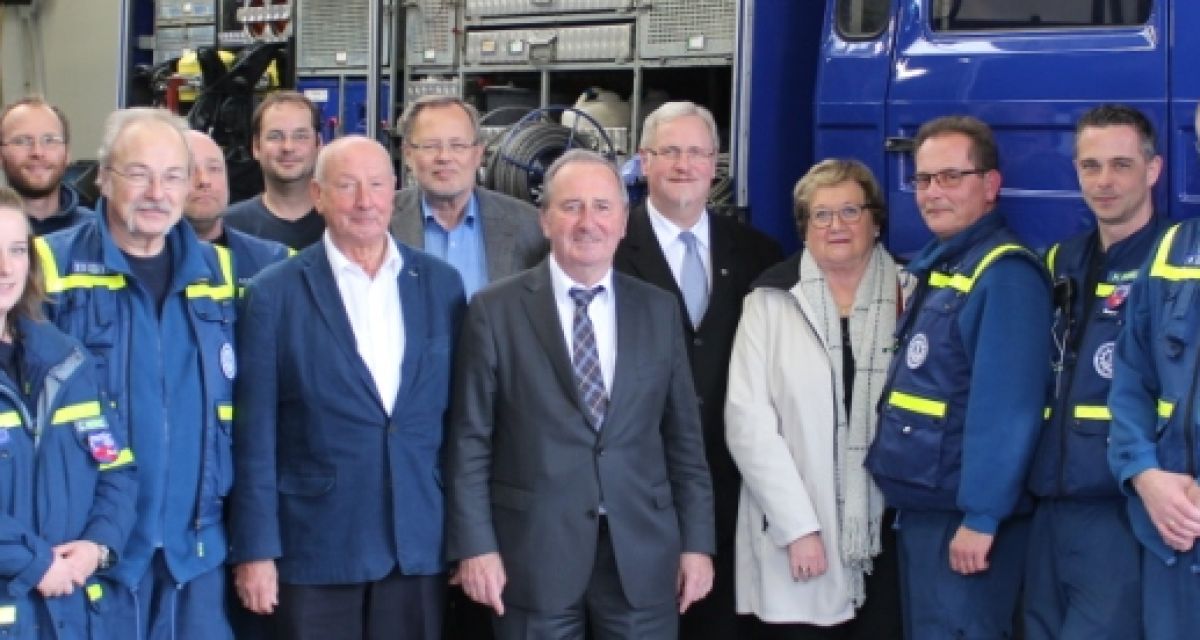 Mitglieder des THW und Politiker vor blauen THW-Fahrzeugen