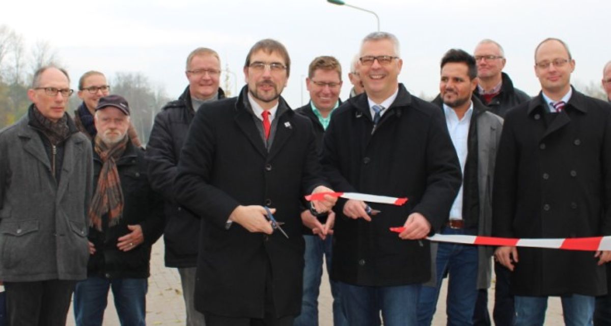 Politiker durchschneiden bei einer Einweihung des Bahnhofs in Sande das obligatorische Band.
