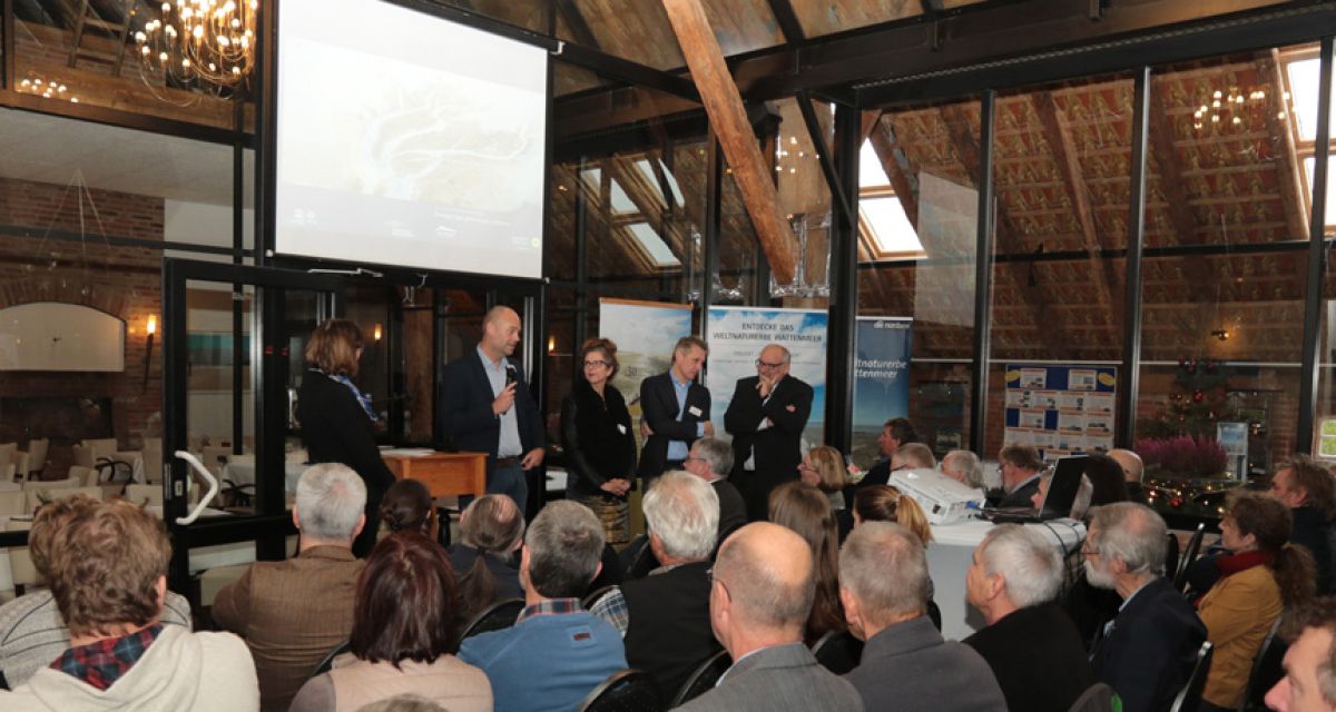 Mehrere Menschen lauschen bei einer Podiumsdiskussion.