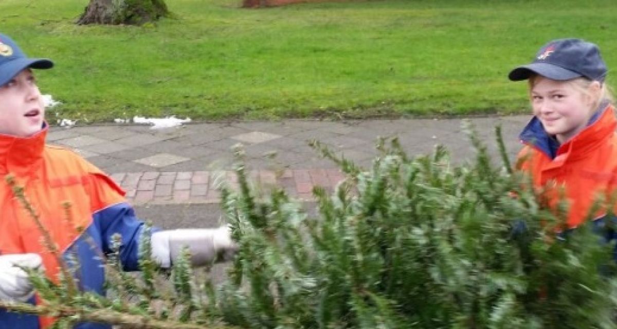 Zwei Mädchen in Feuerwehr-Uniform laden einen Tannenbaum ein.