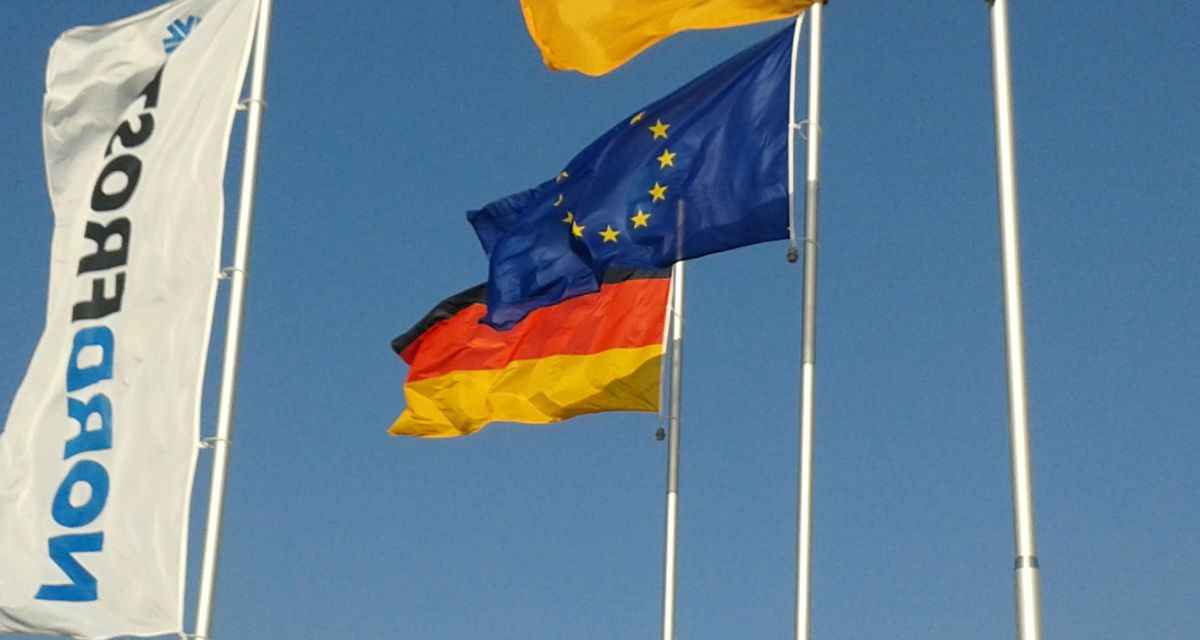 Zu sehen sind Flaggen im Wind. Eine zeigt das Logo von NordFrost, außerdem sind die Deutschlandflagge und die der EU zu sehen. 