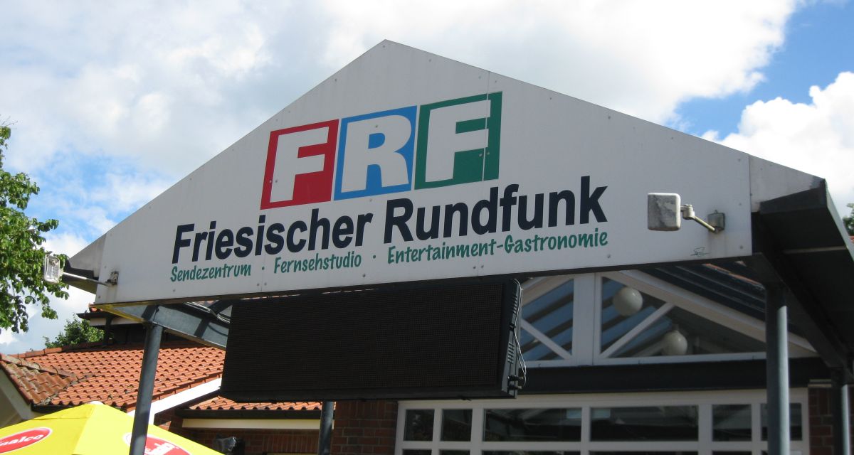 Vor dem Funkhaus in Sande. Es ist das Logo des FRF zu sehen.