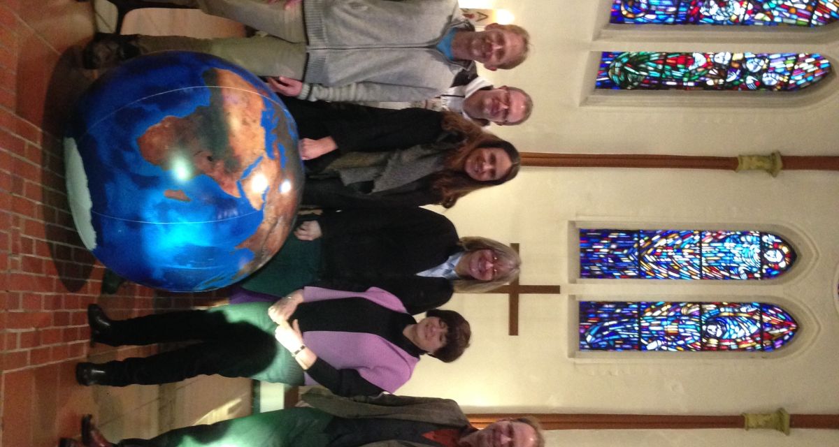 Menschen posieren, hinter einen kleinen Globus stehend, in einer Kirche für die Kamera.