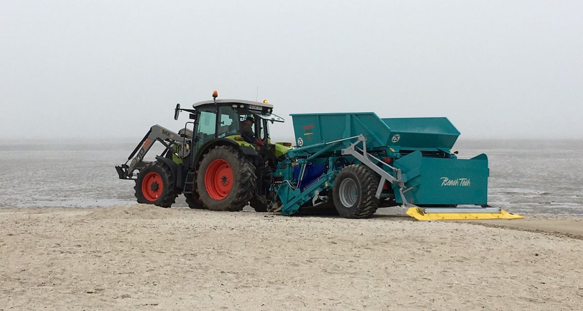 Trecker mit Anhänger am Strand im Einsatz.